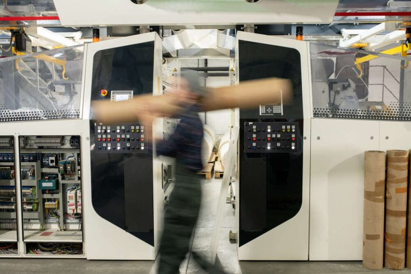 Blurred motion of male worker of contemporary factory carrying large detail